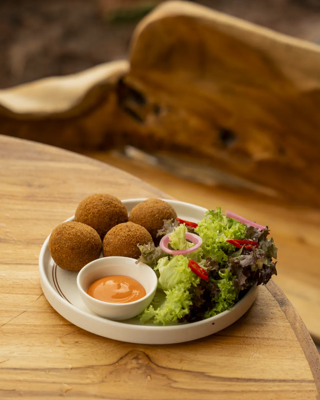 Golden croquettes with a dressed salad and dipping sauce at Nava